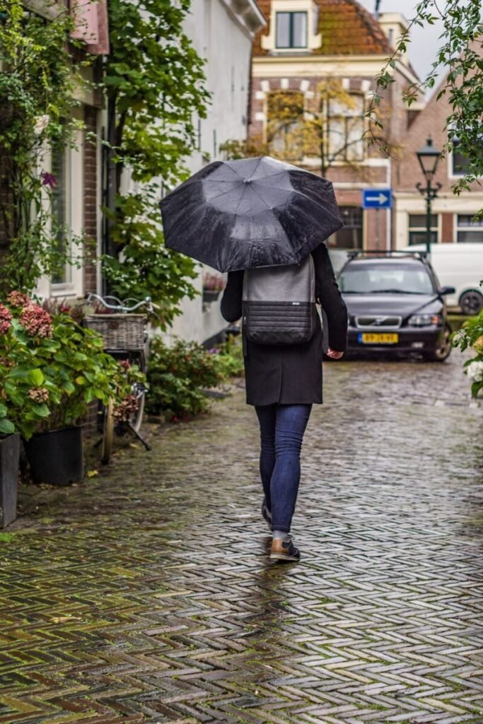 solo woman walking along a rainy London street holding an umbrella, symbolising new horizons and self‑rediscovery