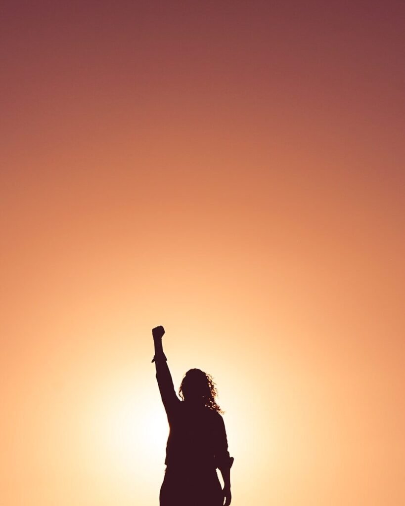 silhouette of woman raising her fist in the air in a confident pose, representing empowerment, independence, and solo travel mindset